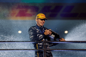 Max Verstappen estourando champagne perto de uma grade no pódio